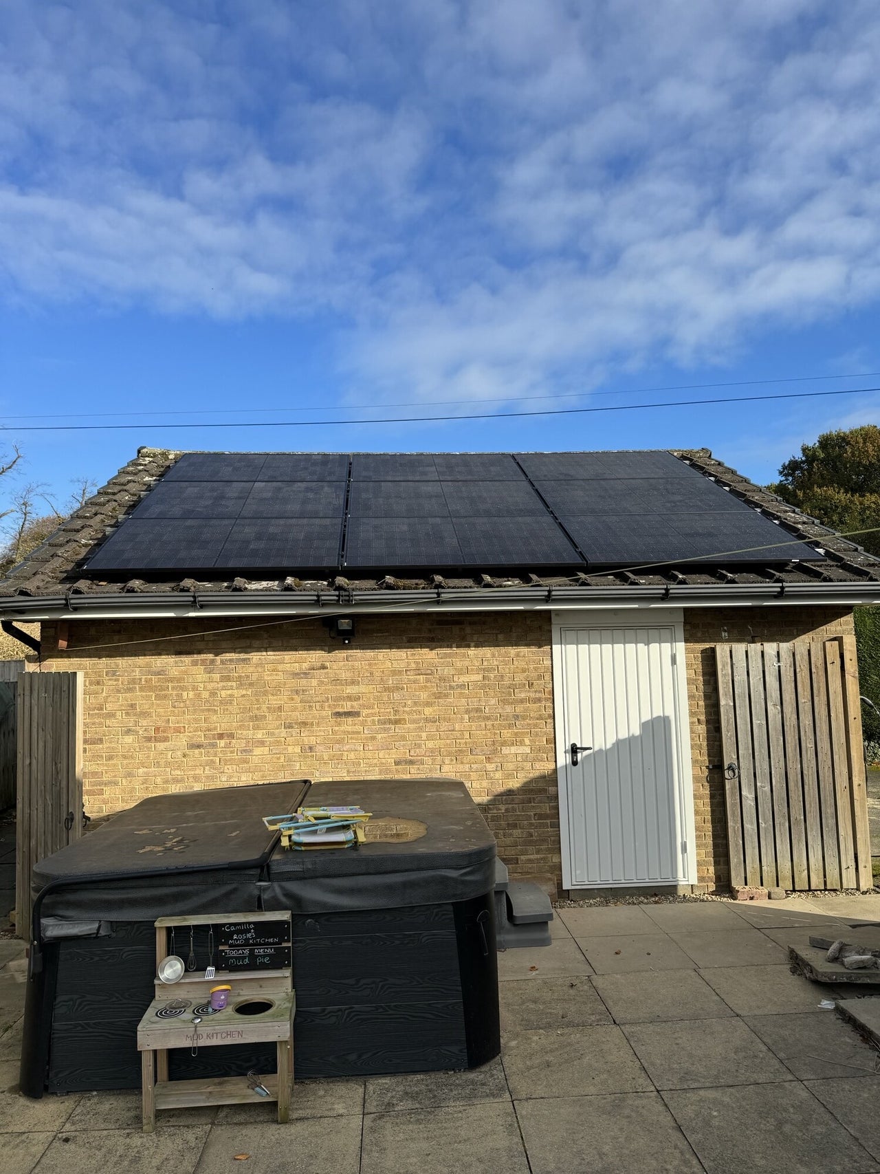 Solar panels installed on a garage roof under a blue sky.